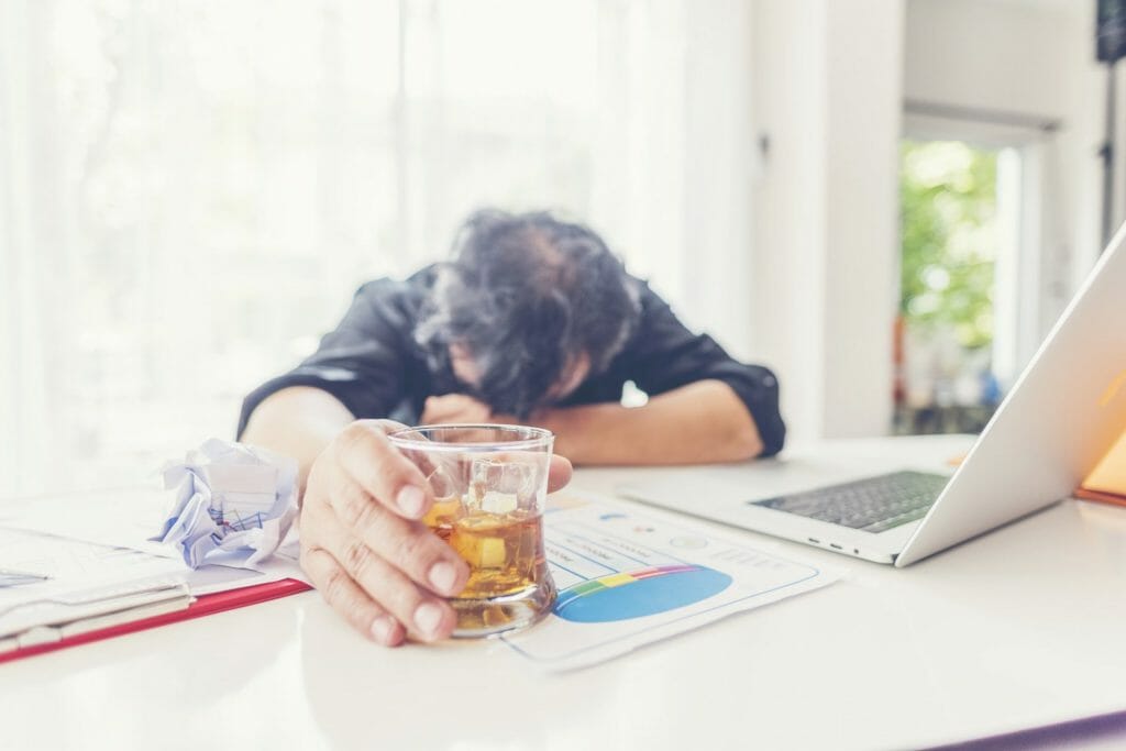 alcohol addiction - drunk businessman holding a glass of whiskey