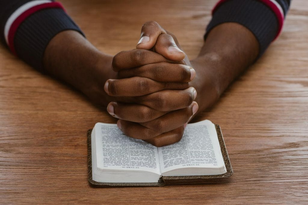 cropped shot of african american man praying with holy bible