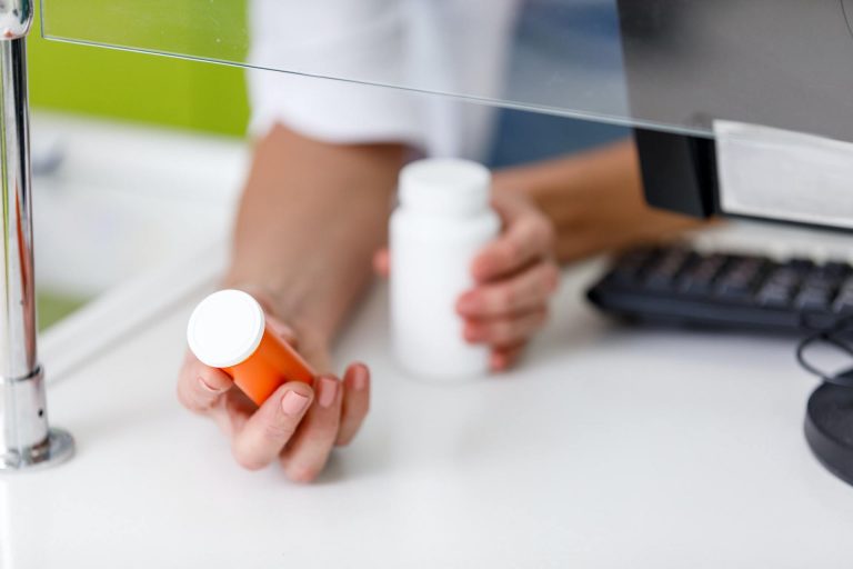 cropped shot of pharmacist holding containers with medication