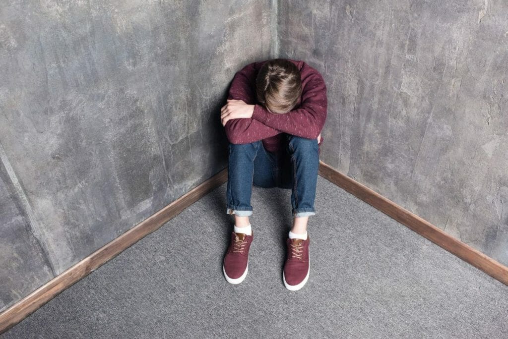 High angle view of depressed teenage boy sitting on floor