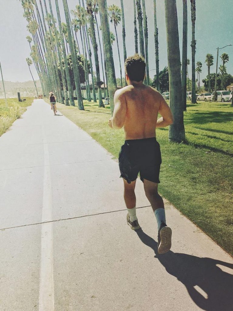 Young man jogging on a bike path at a California beach